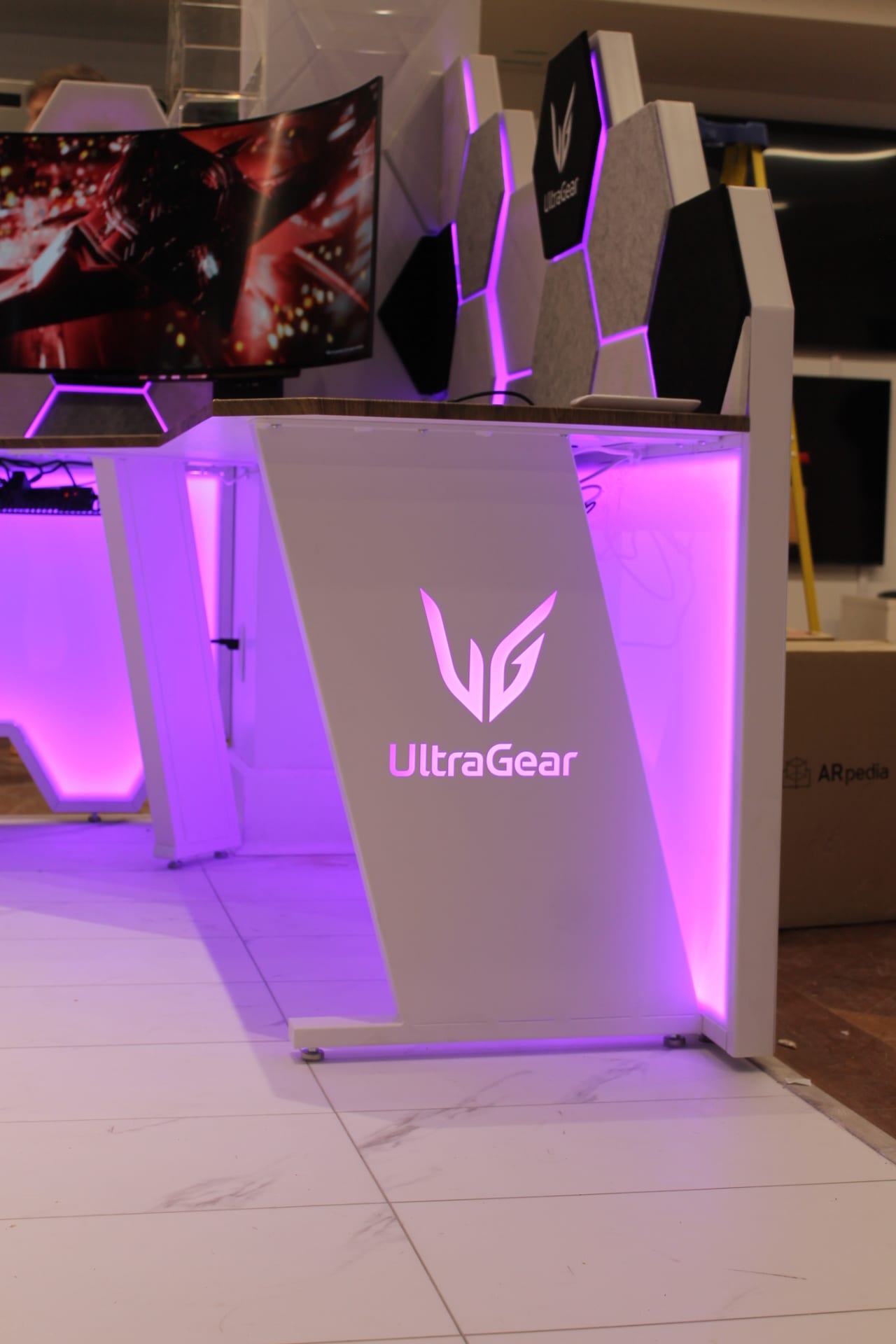 Angled view of an illuminated UltraGear gaming desk station showing its sculptural shape and branding