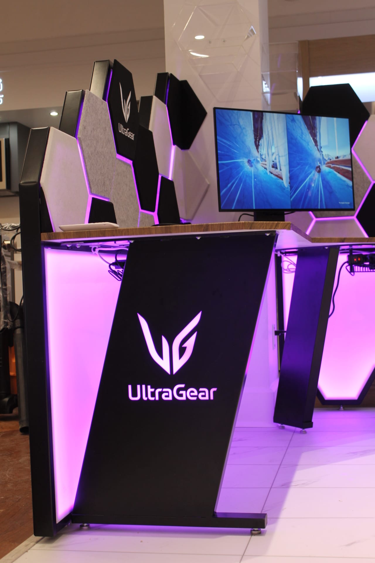 UltraGear branded panel set against the LED-lit hexagonal acoustic backdrop